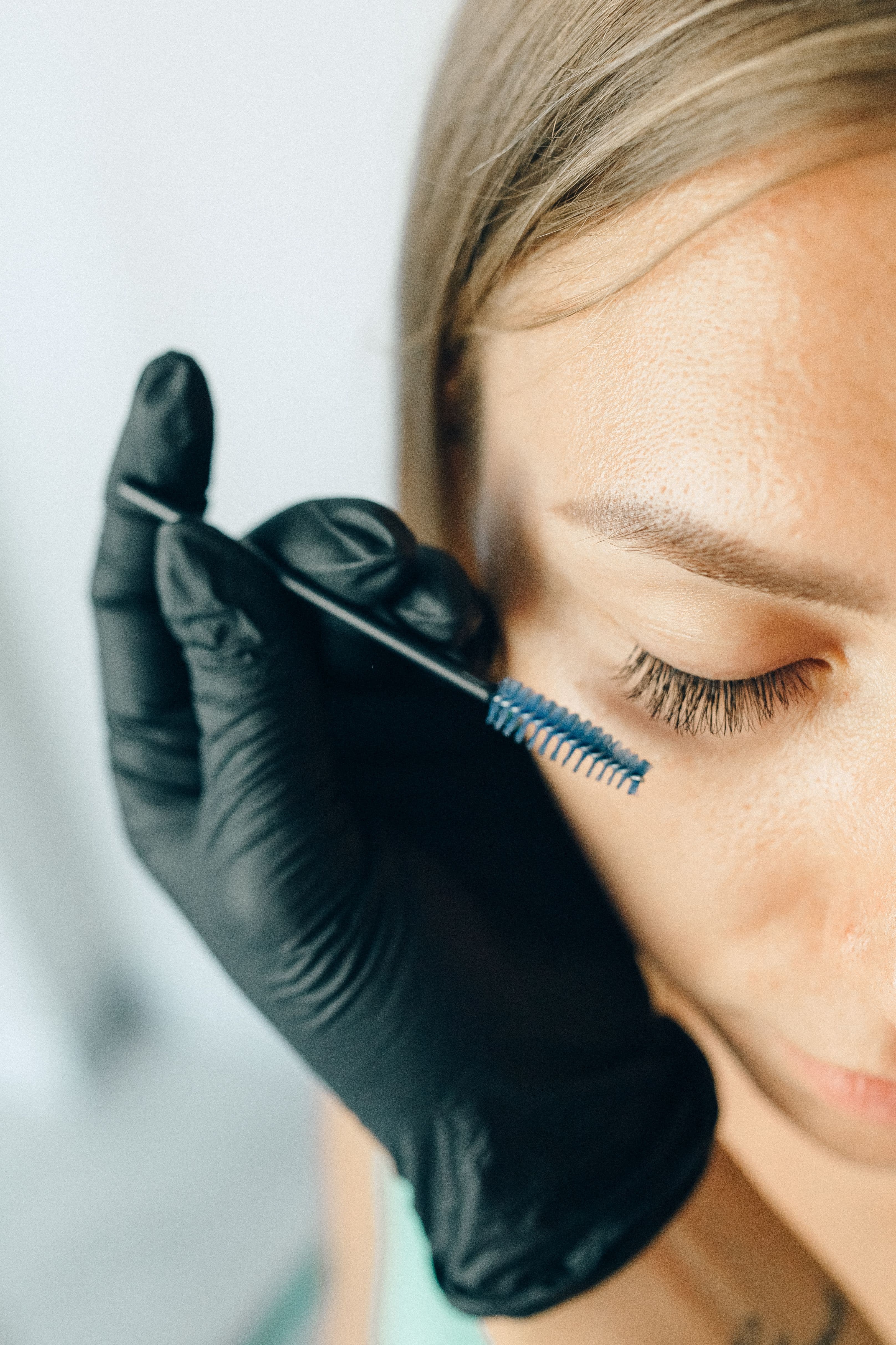 Lash artist grooming eyelash extensions with a spoolie brush